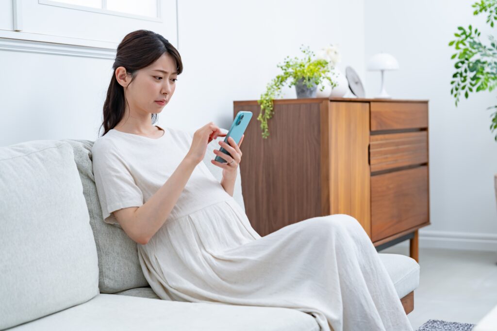 ソファで携帯を持つ女性